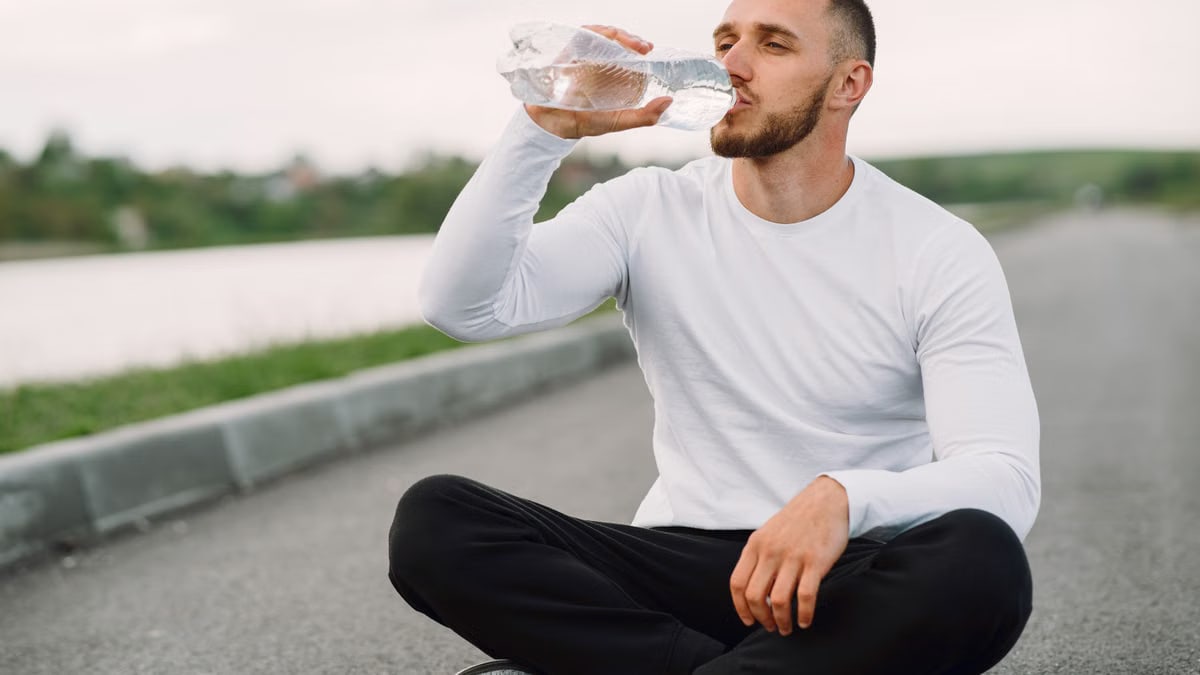 A man in sportswear hydrates outdoors, promoting healthy lifestyle and fitness.